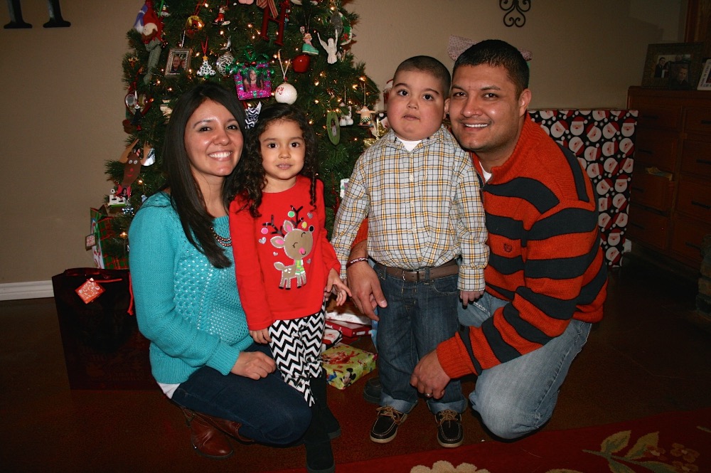 Jace and his family posing for a photo in front of their Christmas Tree.